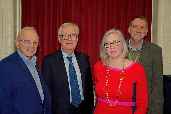 Richard Dickson, Lord Dick Newby, Jenny Wilkinson and Noel Rock standing in front of a red curtain.