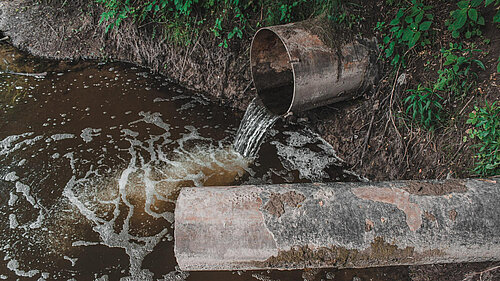 Dirty water pouring from pipe into water course